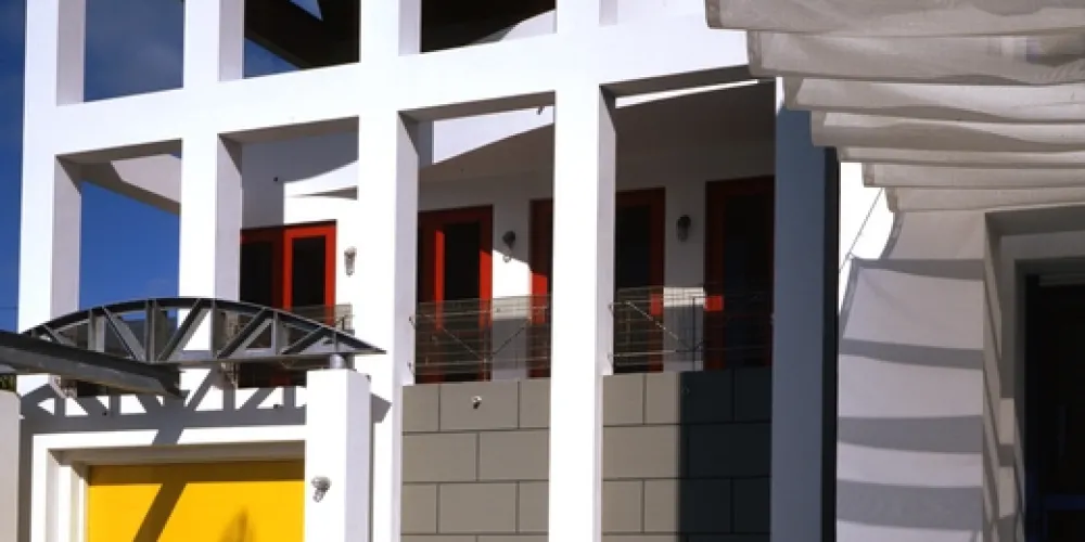 The entrance exudes modern tropical charm, featuring geometric designs and vibrant accents. A combination of natural and robust materials gives a warm and inviting feeling to the architectural facade.

