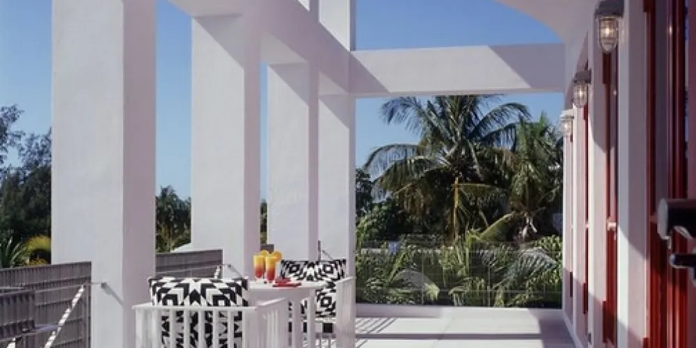 A sun-dappled upper balcony invites leisure with modern seating and panoramic views, offering a perfect spot for morning coffee or sunset relaxation, integrating architectural elegance with nature.

