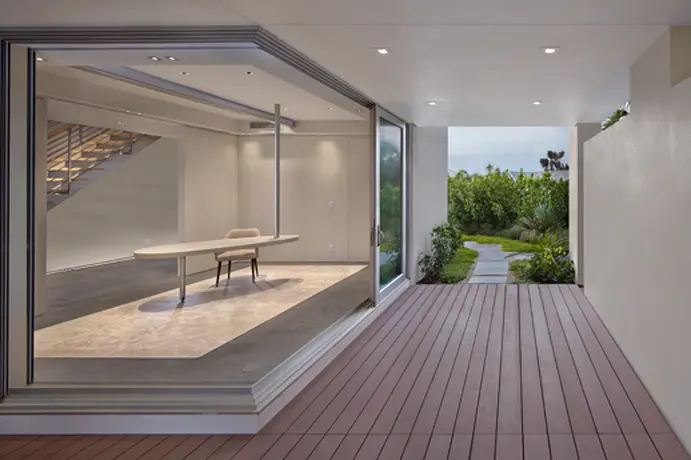 This Home includes innovative indoor-outdoor office space marked by minimalist design features. The expansive glass walls create a seamless transition between the interior and the exterior deck area, promoting a sense of openness and connectivity with nature. 
