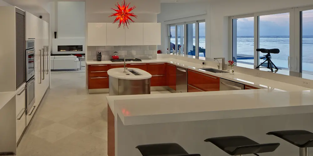 The kitchen combines functionality and style with high-end appliances and sleek surfaces in a bright, open layout. The design allows for ocean views, connecting culinary experiences with the surrounding landscape.
