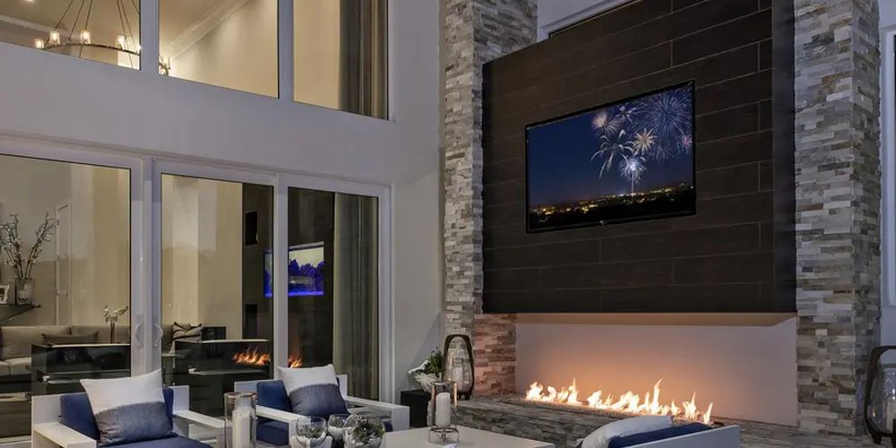 The outdoor lounge area exudes warmth and comfort, featuring a modern fireplace integrated into a stone-clad wall. The seating arrangement is contemporary and inviting, complemented by large windows that create a seamless transition between indoor and outdoor living spaces.