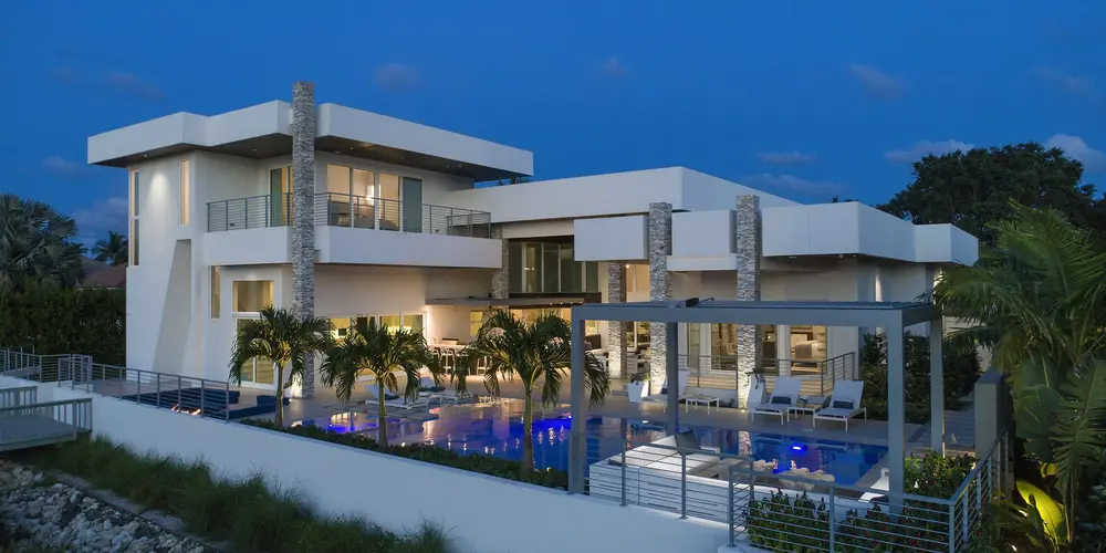 The exterior glow highlights the home's modern exterior, incorporating stone pillars as accents into clean lines. The lighting emphasizes architectural details, creating a striking visual statement against the night sky.