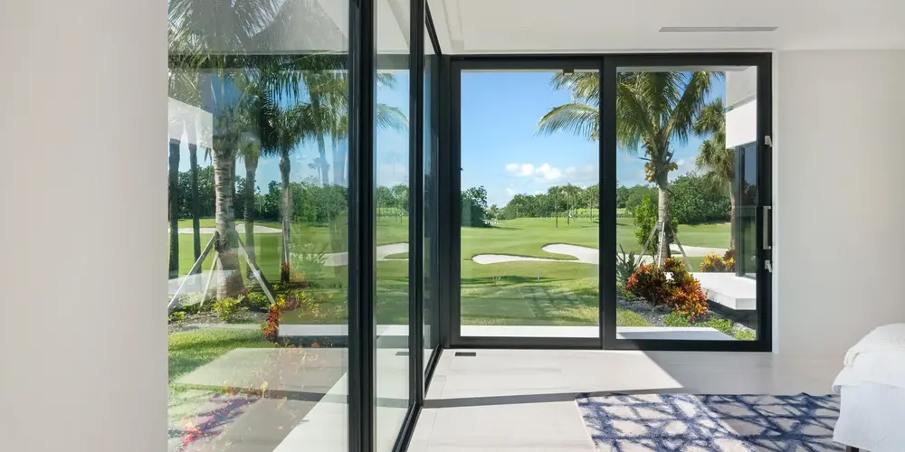 The bedroom's vast glass installations create an uninterrupted view of the verdant golf course, merging indoor comforts with the scenic outdoors. 
