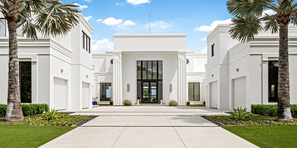 As you approach this modern residence, the architectural style is defined by its imposing yet elegant use of columns, which prominently frame the entrance. These columns serve as a nod to classical influences while maintaining a contemporary aesthetic, blending the old with the new. The home's facade, with its minimalist lines and symmetry, creates a sophisticated entrance that commands attention. The overall style is reminiscent of neoclassical architecture, but with a modern twist that emphasizes simplicity and elegance.