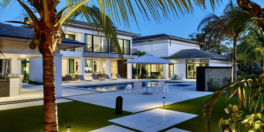 The pool area serves as an outdoor oasis, surrounded by tropical landscaping and ample lounging space. The combination of water and greenery provides a serene retreat for relaxation.