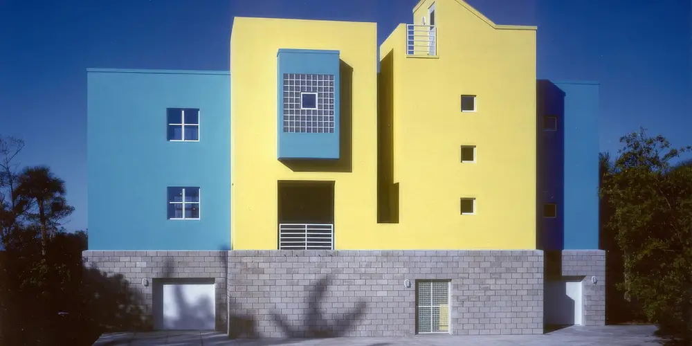 Explore vibrant modern architecture through a striking facade featuring lively yellow and blue hues. This dynamic building showcases a blend of creative and tranquil design elements, enhanced by contrasting textures for a contemporary aesthetic.