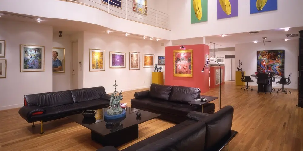 Step into a stylish living area enriched with colorful artwork and refined design. This modern space balances calm neutral tones with cultural vibrancy, highlighted by warm wooden flooring and sophisticated leather seating.