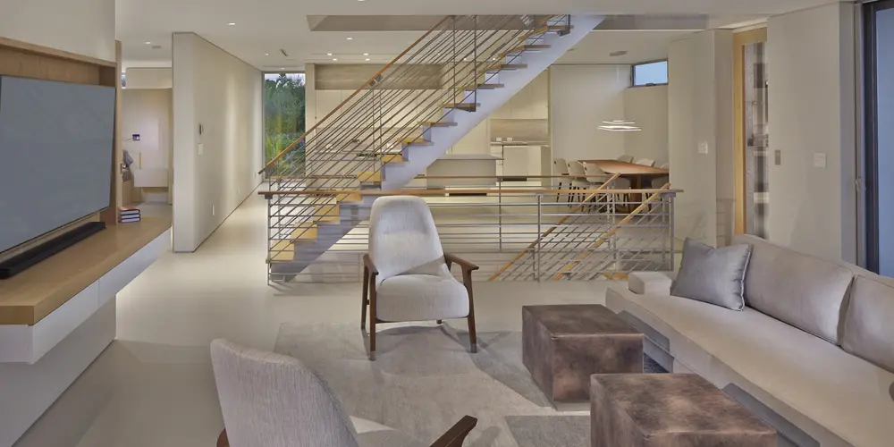 A cohesive and open living space reflects modern comfort and aesthetic continuity, enhanced by strategic lighting and purposeful layout. The stairway integrates smoothly with the living space, accentuating architectural precision.

