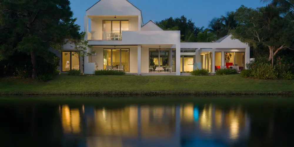 This view from the lake highlights the home's symmetrical design, with expansive glass doors emphasizing its connection to the natural surroundings and creating a picturesque reflection at dusk.