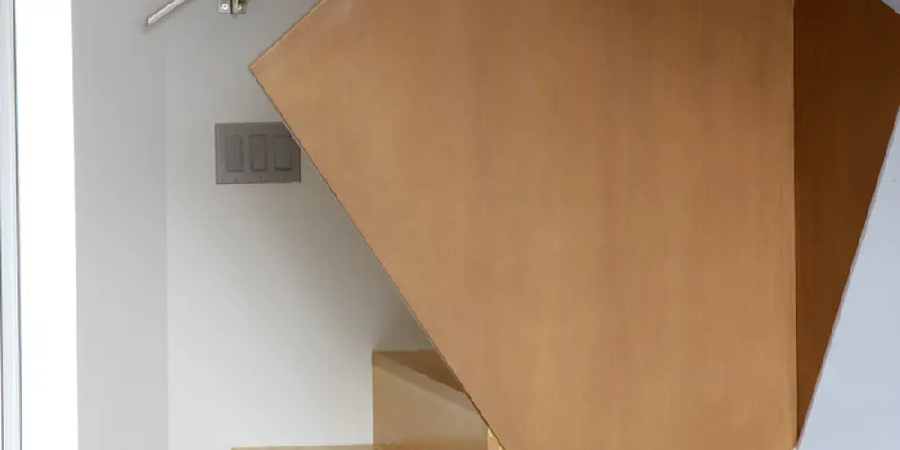 This image highlights a striking geometric staircase that blends wood's warmth with sharp angular lines. The staircase features warm finished wood and innovative design.