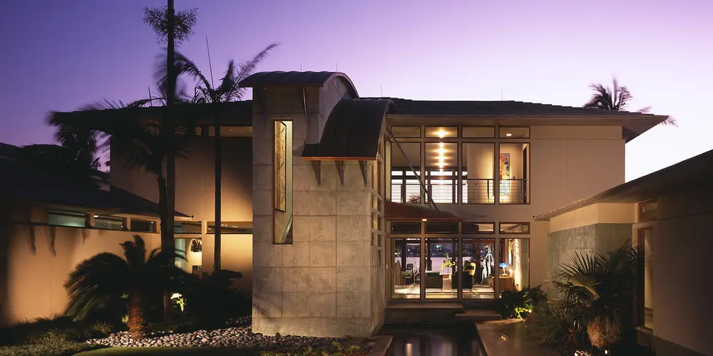 This evening view reveals the home’s captivating architectural design, with dramatic lighting that enhances its elegance and integrates harmoniously with the natural landscape.