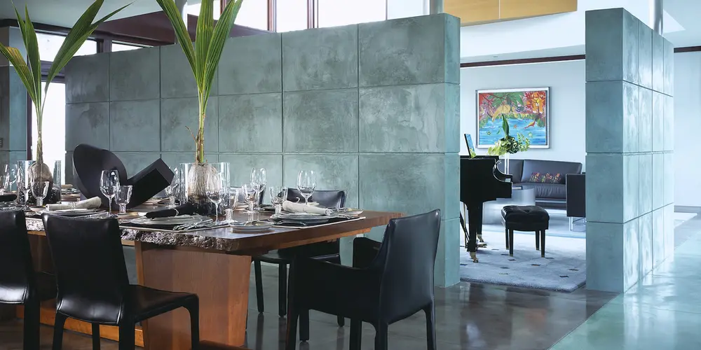 This space showcases an open-plan design with concrete partition walls that subtly separate different areas. The combination of natural wood elements with polished concrete floors creates an aesthetic that is warm yet modern.
