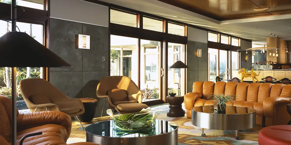 The living room combines rich textures and warm colors within a functional, luxurious space. Earth-toned leather seating, colorful area rugs, and stylish furniture pieces exude comfort while fostering a sense of stylish coziness.

